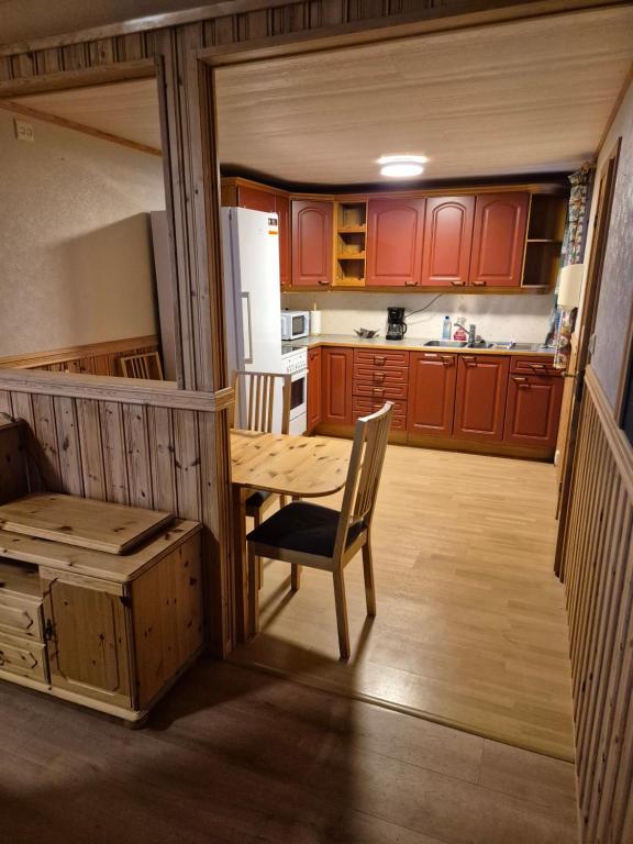 eine Küche mit roten Schränken und einem Holztisch in der Unterkunft The Blue house apartment in Andøya