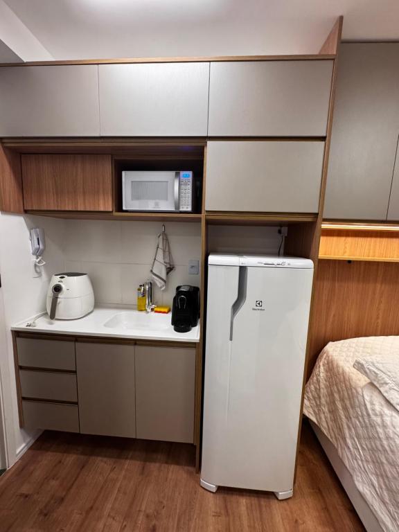 eine kleine Küche mit Kühlschrank und Mikrowelle in der Unterkunft Studio Apartamento no Morumbi próximo ao Estádio Morumbi estação de ônibus metrô e shopping in São Paulo