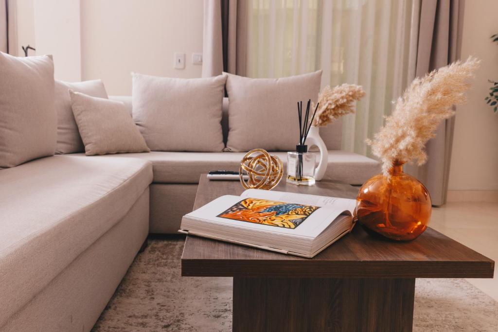 a living room with a couch and a table with a book at VIOLA by Elegant Hospitality in Cairo