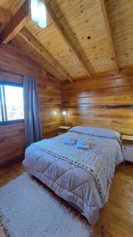 Un dormitorio con una cama en una cabaña de madera. en Entre Sierras y Sueños, en Villa Yacanto