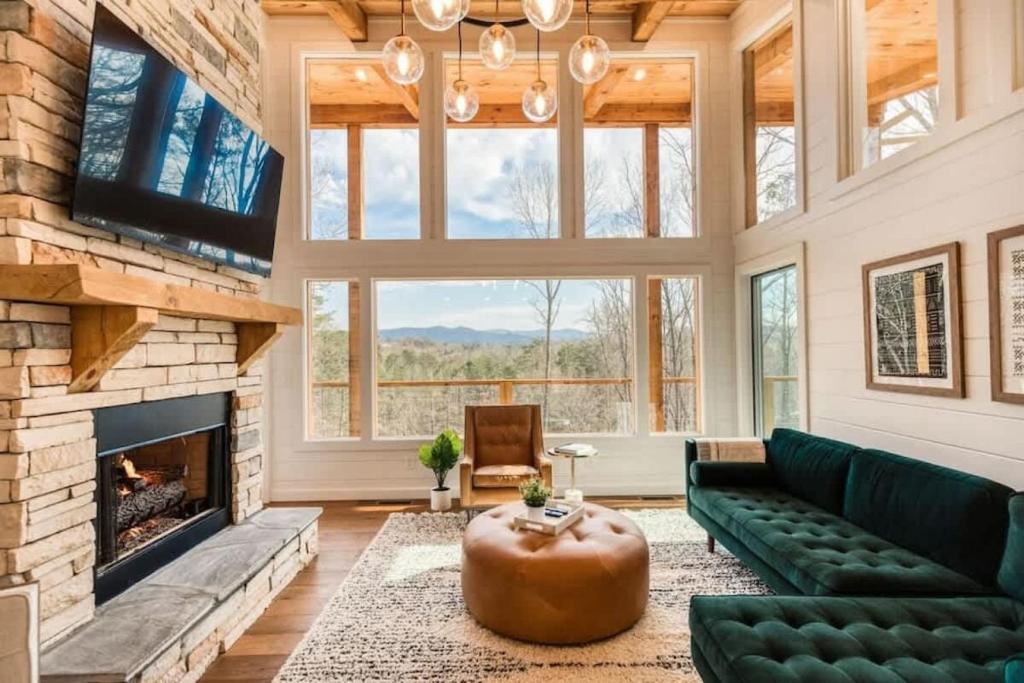 ein Wohnzimmer mit Kamin und einer grünen Couch in der Unterkunft Modern Luxury - EV Charger Hot Tub & Epic Views in Blue Ridge