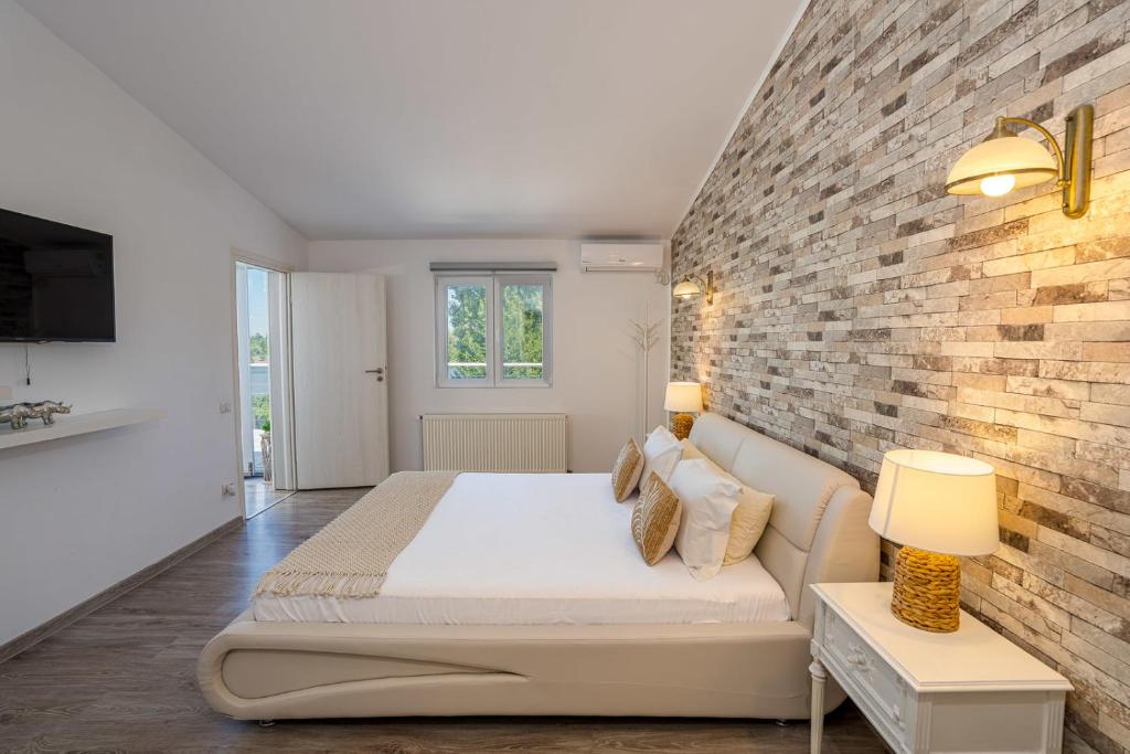 a bedroom with a bed and a brick wall at Sara's Vila in Tufanul