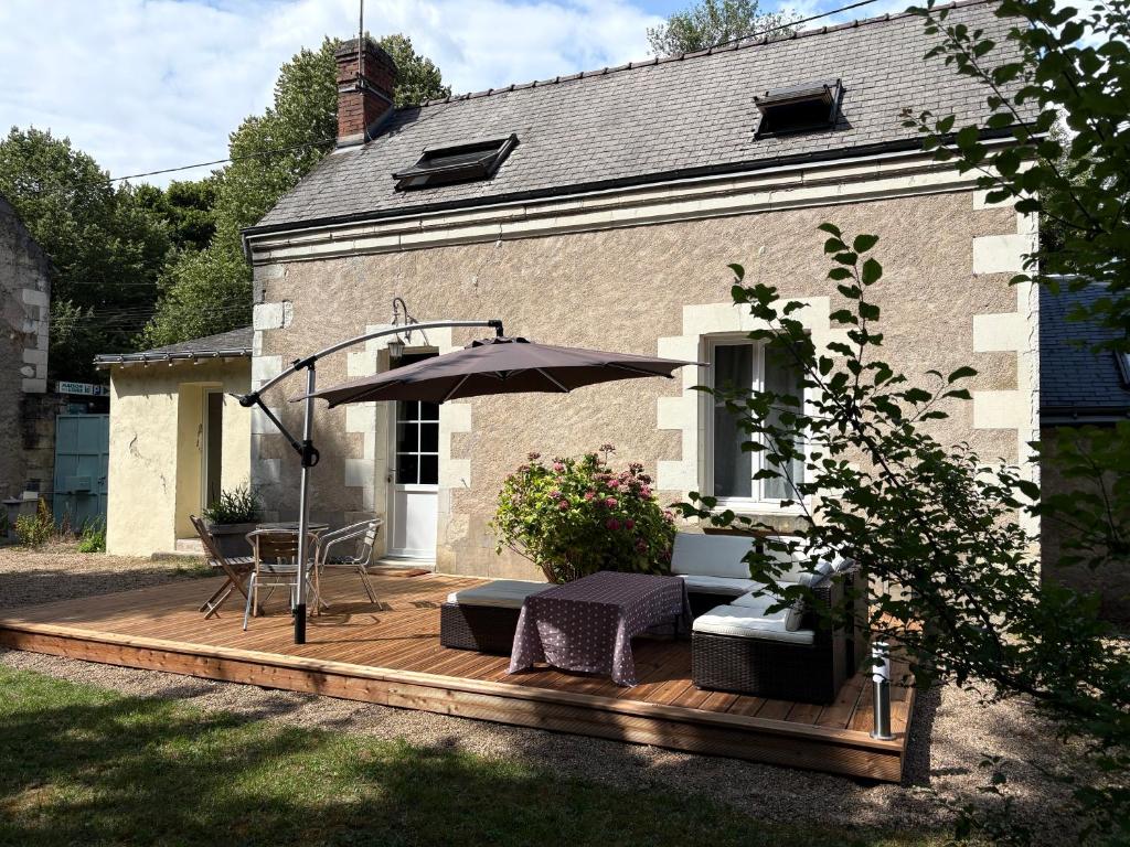 eine Holzterrasse mit Tisch und Sonnenschirm in der Unterkunft Maison de charme en bord de Loire in Montlouis-sur-Loire