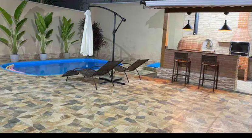 アチバイアにあるLinda casa em condominioの椅子のあるパティオとバーのあるプール