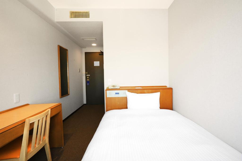 a small room with a bed and a desk at Smile Hotel Sugamo in Tokyo