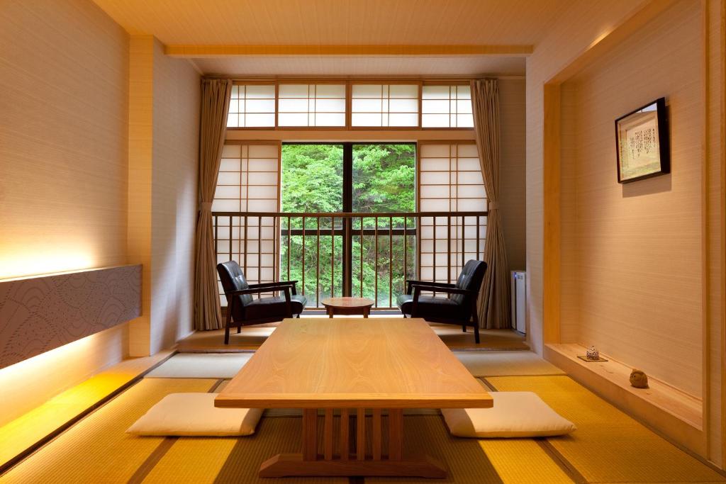 a room with a table and chairs and a window at Shosuke-no-Yado Takinoyu in Aizuwakamatsu