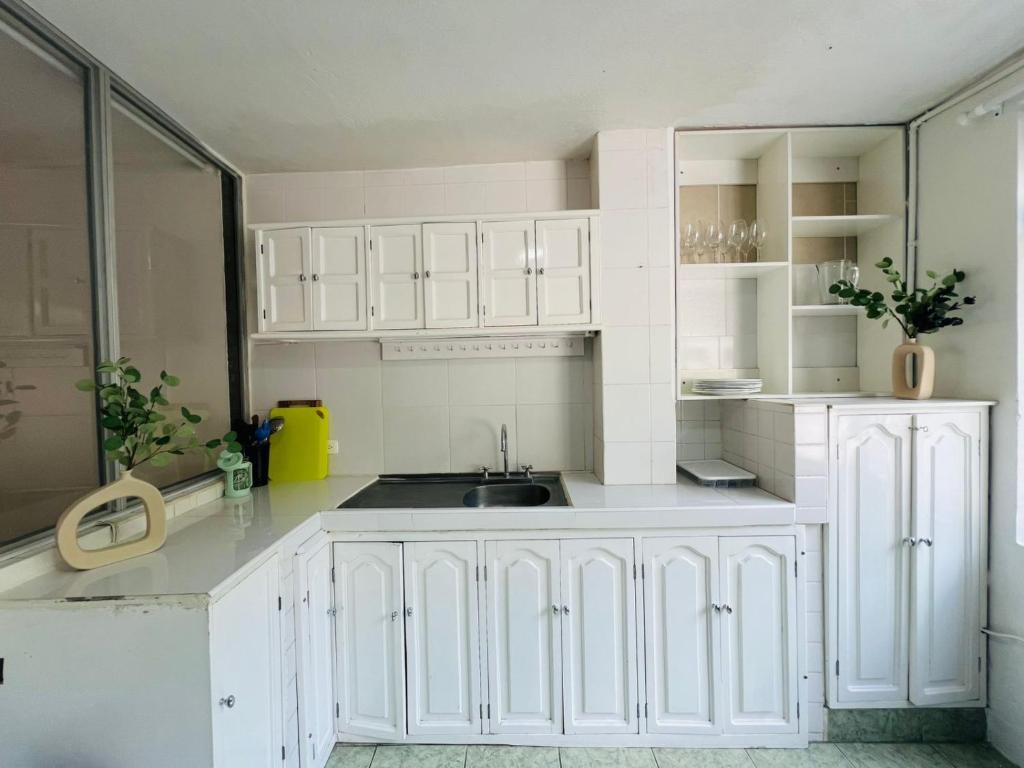 a white kitchen with white cabinets and a sink at Santa Clara Apartment 3 Bedroom 2 Bath in Baños