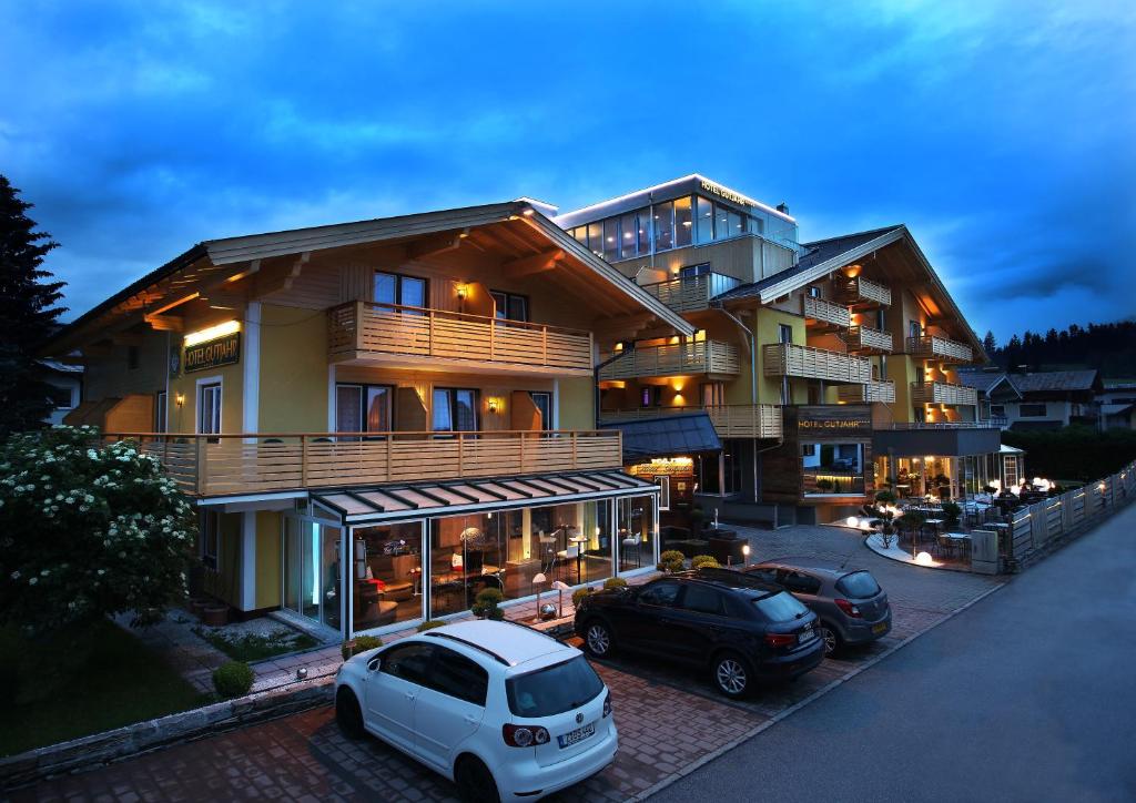 una casa grande con dos coches estacionados frente a ella en Aktiv- und Wellnesshotel Gutjahr, en Abtenau