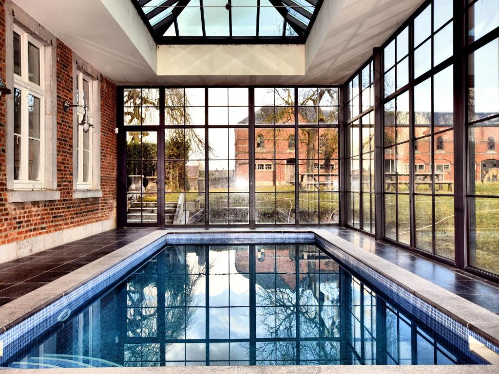 une piscine intérieure dans une maison avec des fenêtres dans l'établissement Stylish Stay with Sauna, à Mesnil-Saint-Blaise