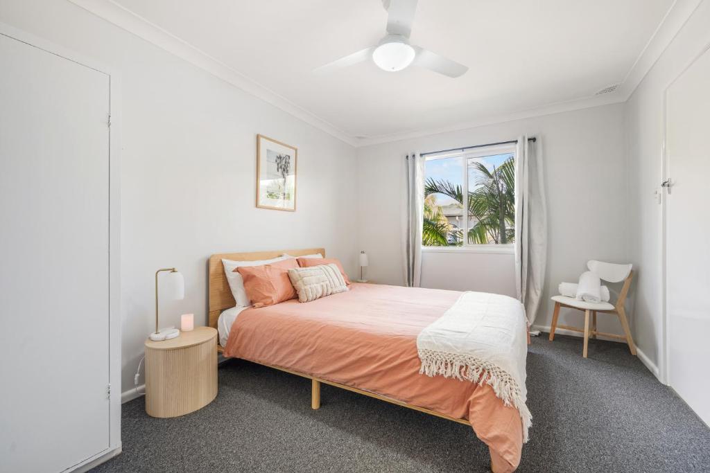 a white bedroom with a bed and a window at Beach Shack No. 6 in Crescent Head