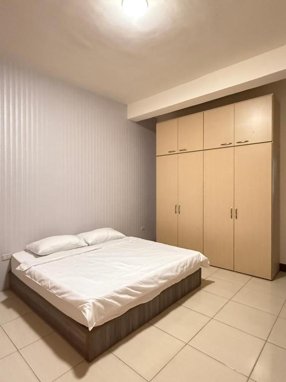 una camera da letto con letto con lenzuola e armadi bianchi di Aomori Travel a Hung-i-li