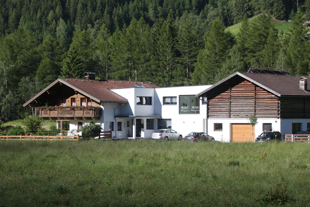 eine Gruppe von Häusern auf einem Feld mit Bäumen in der Unterkunft Apart Armin in Längenfeld