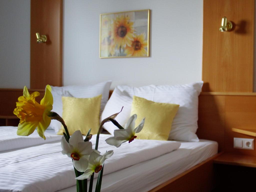a bedroom with a bed with a vase of flowers on it at Gartenpension Fischl in Mörbisch am See