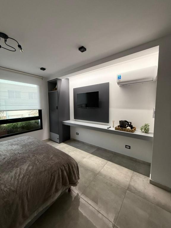 a bedroom with a bed and a flat screen tv at Botanic Apart in Villa María