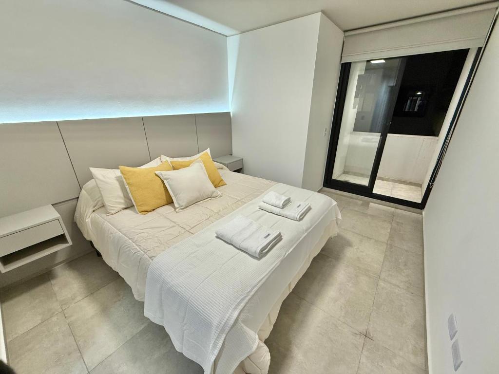 ein Schlafzimmer mit einem großen weißen Bett mit gelben Kissen in der Unterkunft Petit Premium Nueva Cba - Oulton in Cordoba