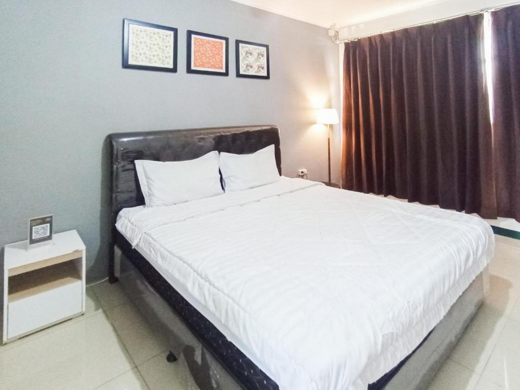a bedroom with a large white bed with a window at Gatsu Resort RedPartner at Karangploso in Karangploso