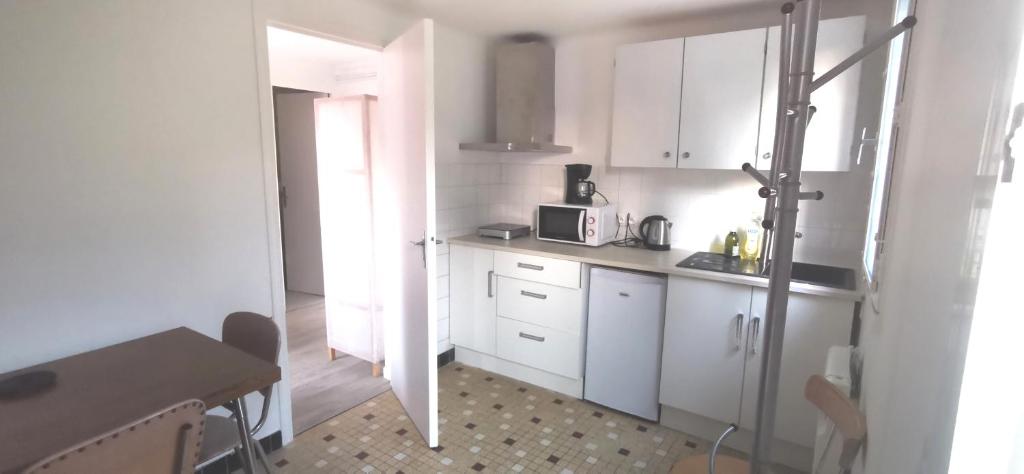 a small kitchen with white cabinets and a microwave at Cottage studio in Tregueux