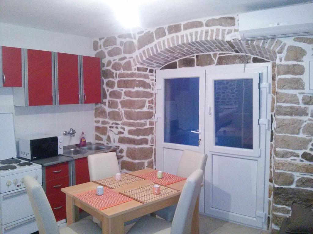a kitchen with a table and a stone wall at Holiday House Popovic in Sućuraj