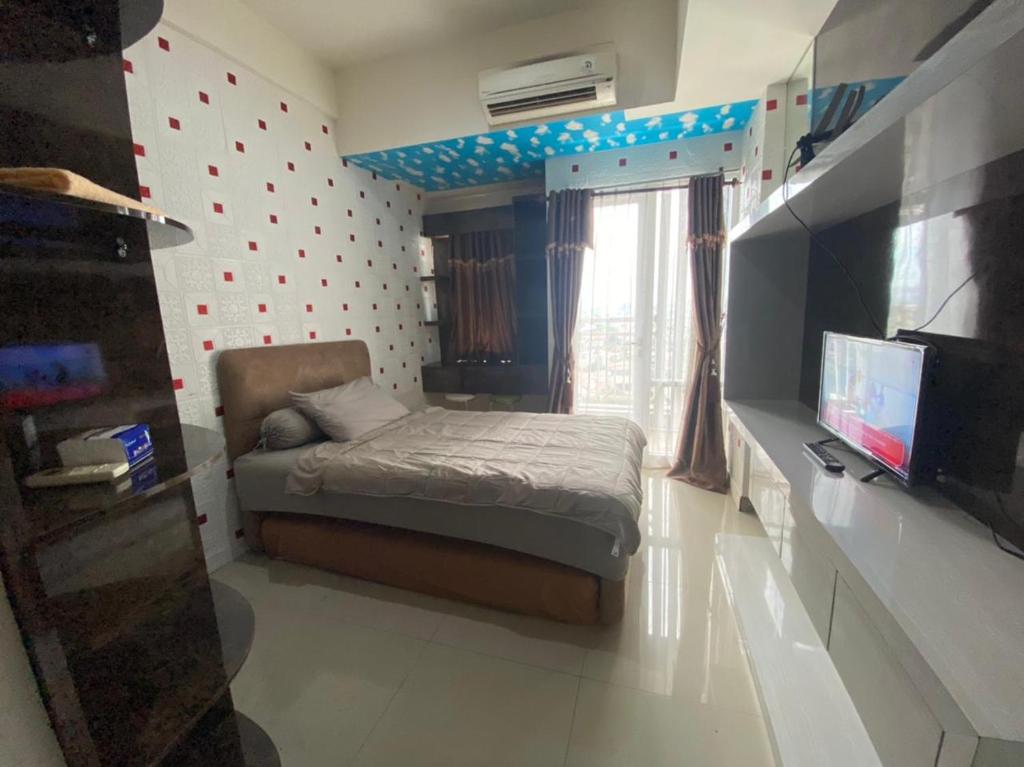 a small bedroom with a bed and a television at Apartemen Vida View Unit 9J By Millpro in Pampang