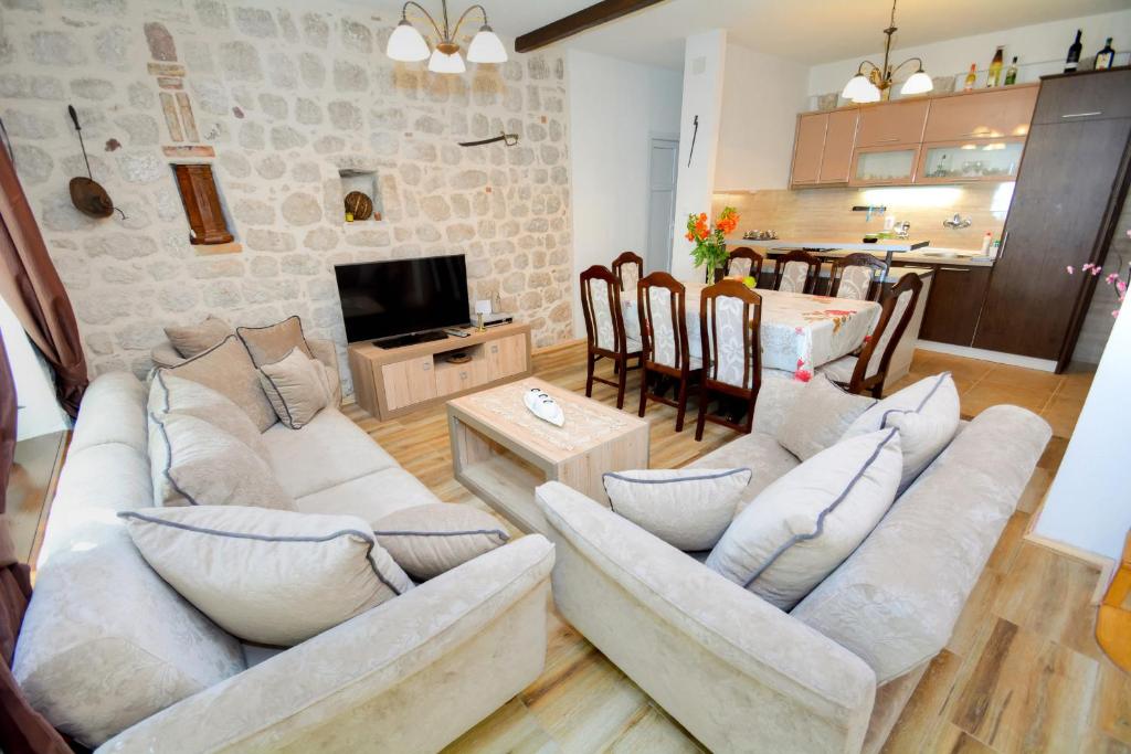 una sala de estar con 2 sofás blancos y una mesa. en Apartments Krivokapic, en Perast