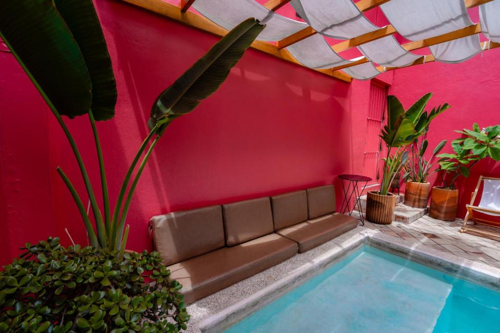 オアハカにあるCasa de Arte Hotel Boutiqueのピンクの壁の隣にソファがあるリビングルーム