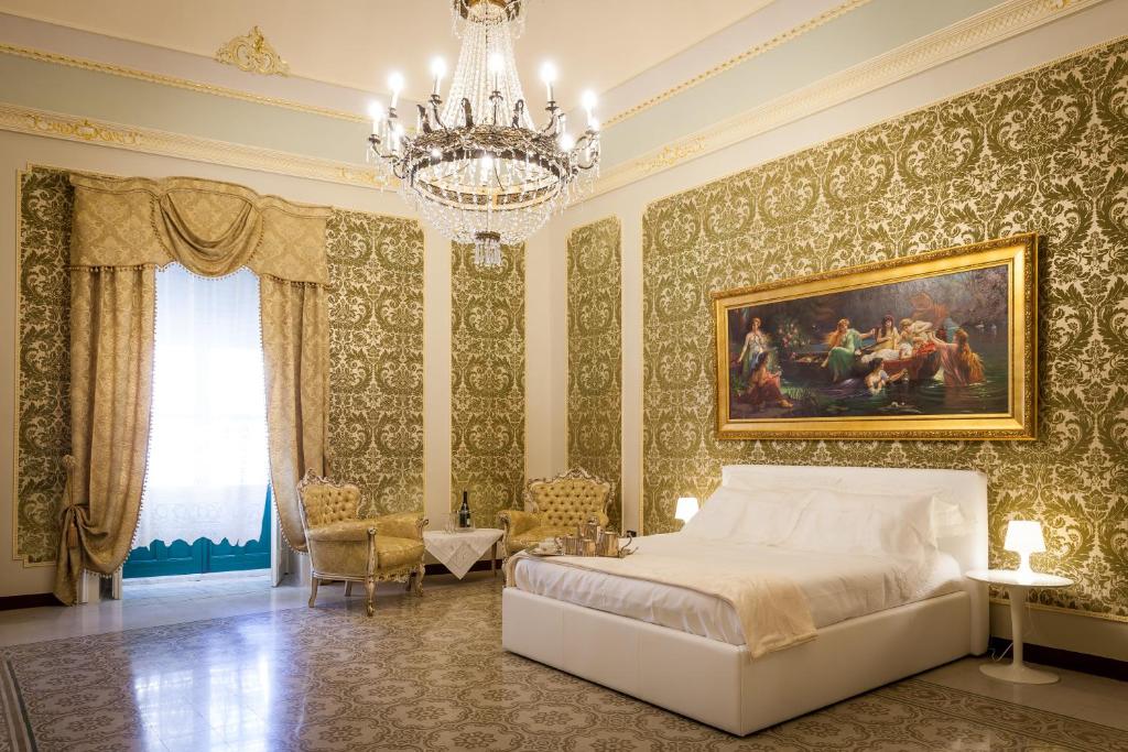 Un dormitorio con una cama grande y una lámpara de araña. en Palazzo Montalbano, en Scicli
