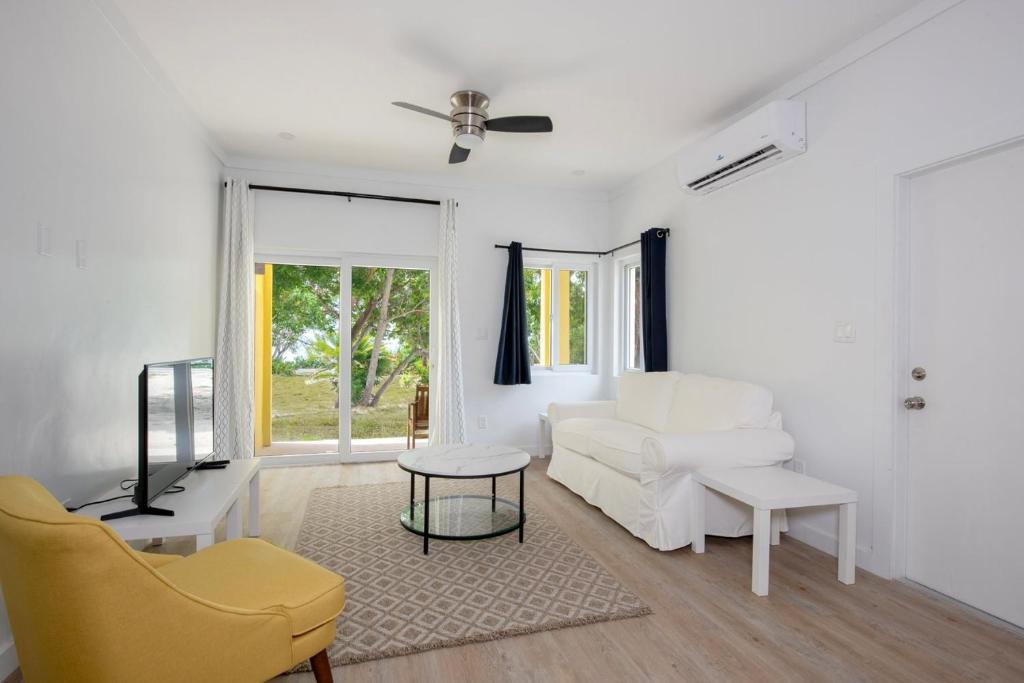 a living room with a white couch and a table at Laughing Bird 1BR #1 - Brand New Stylish Apartment, Pool, Beach condo in Colebrooke Dale
