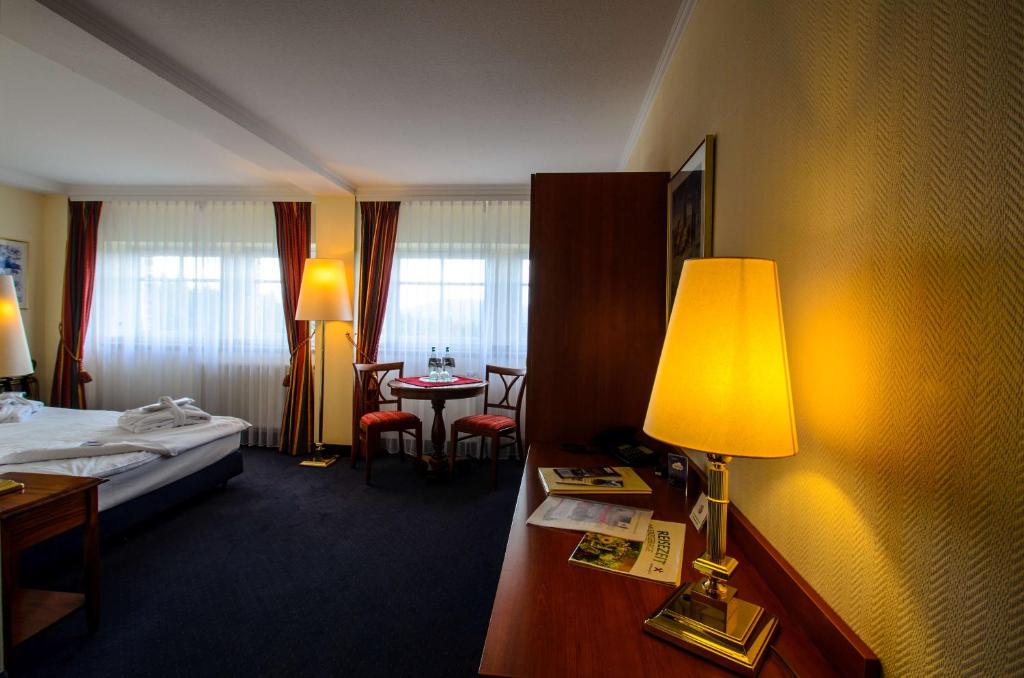ein Hotelzimmer mit einem Bett und einem Schreibtisch mit einer Lampe in der Unterkunft Hotel Sachsenbaude Oberwiesenthal in Kurort Oberwiesenthal