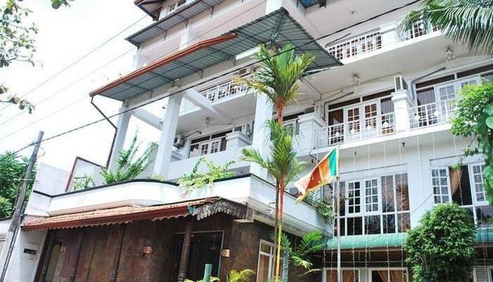 a large white building with a flag in front of it at Nathaliya Tourist Hotel in Seeduwa