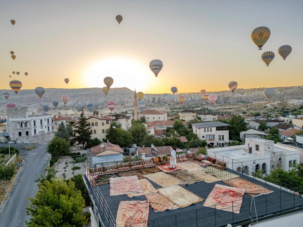 a group of hot air balloons flying over a city at Latona Stone Palace in Nevsehir