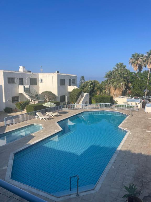 a large swimming pool with blue water at Pelagos Hill Apartment in Paphos
