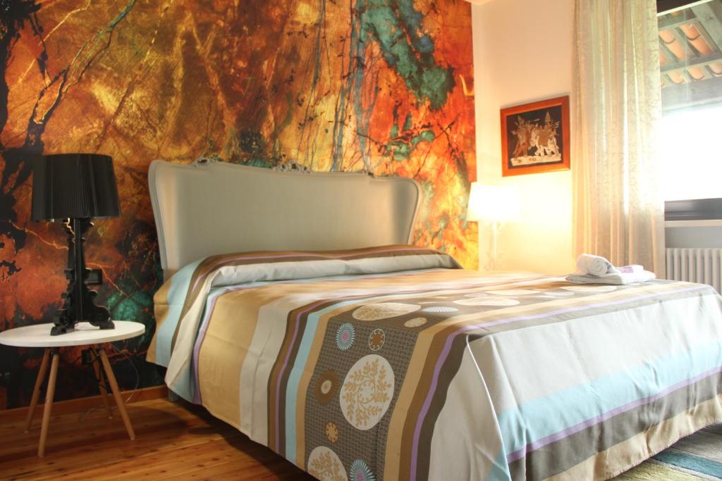 sypialnia z łóżkiem z kolorową ścianą w obiekcie Tenuta Adriana w mieście Masserano