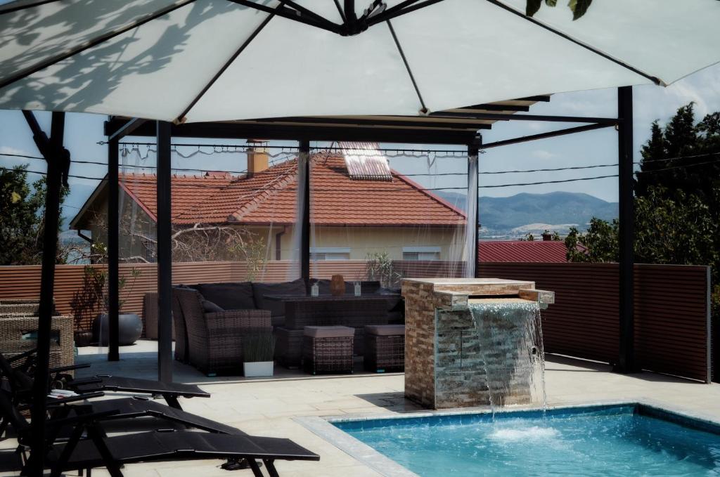 a patio with an umbrella and a swimming pool at Villa Toni Mediterranean Family Lake Retreat in Star Dojran