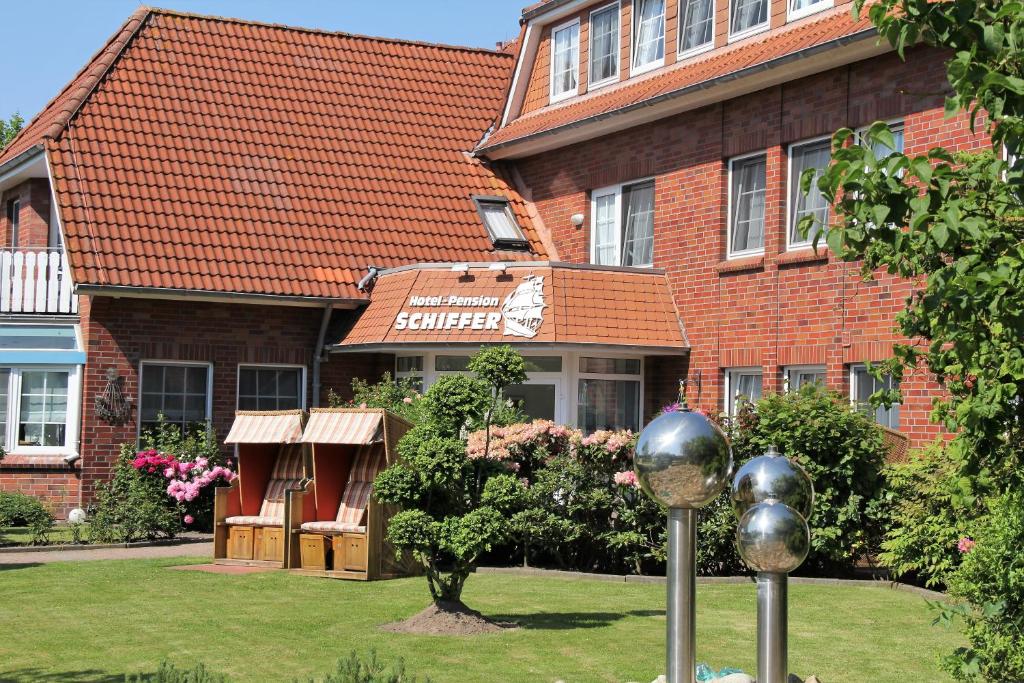 a brick building with a tree in front of it at Hotel Schiffer in Bensersiel