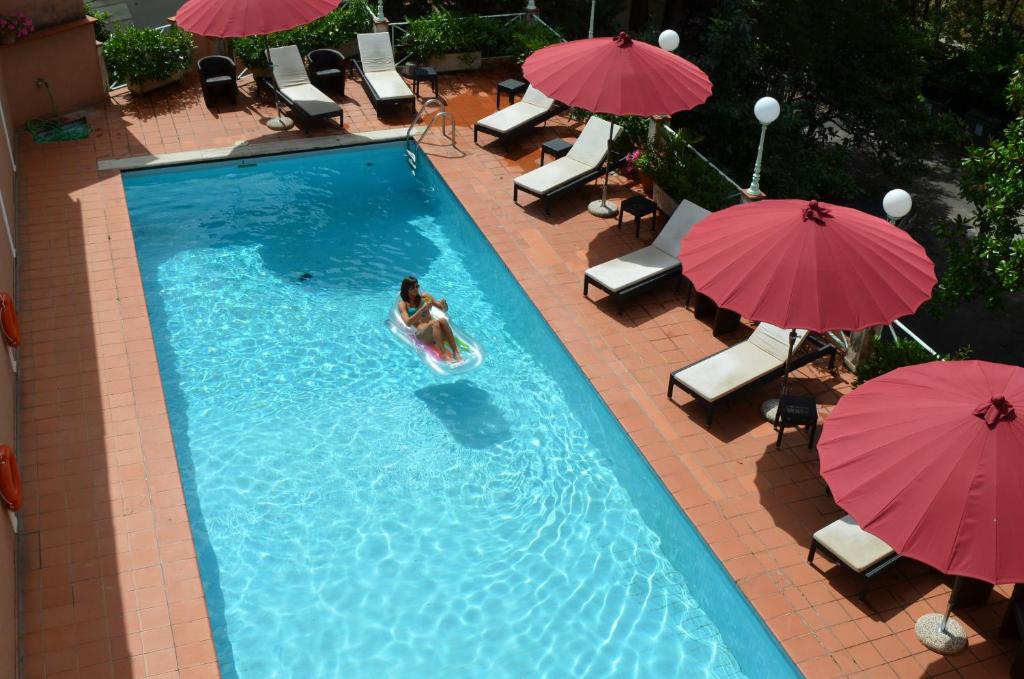 eine Person in einem Pool mit Sonnenschirmen in der Unterkunft Grand Hotel Nizza Et Suisse in Montecatini Terme