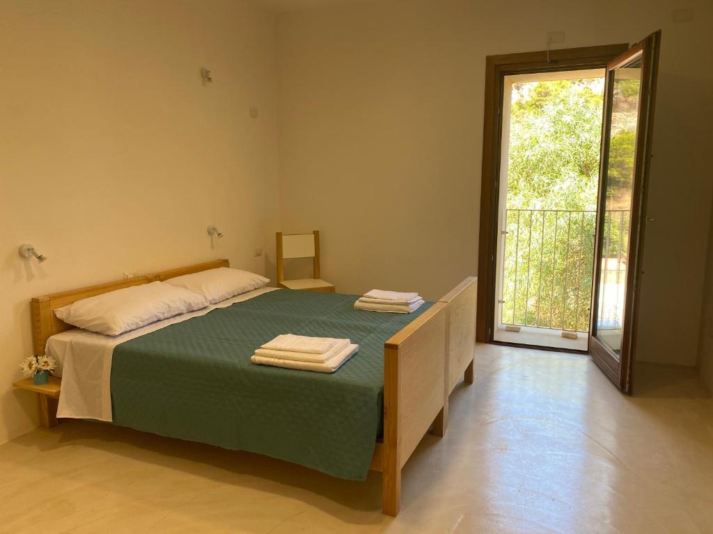 a bedroom with a bed and a sliding glass door at Posada Eco-Ostello di Buggerru in Buggerru