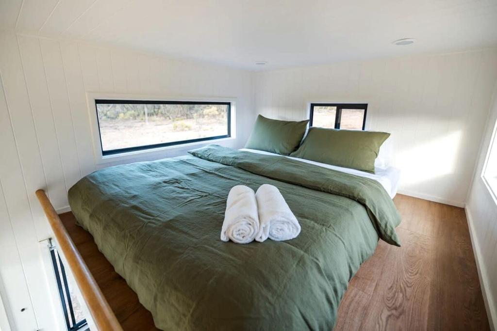 a bedroom with a large bed with towels on it at Lovely Tiny House with Barbecue in Maiden Gully, Victoria in Woodvale