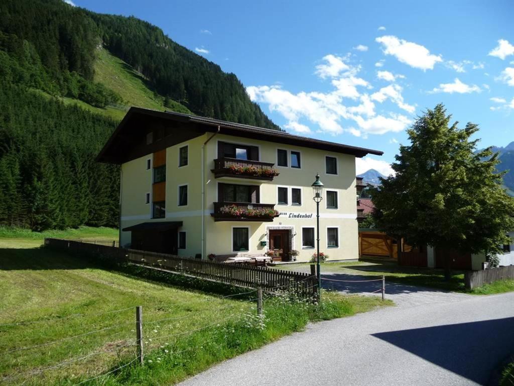 a large white house on a hill with a tree at Lindenhof**, Pension in Rauris