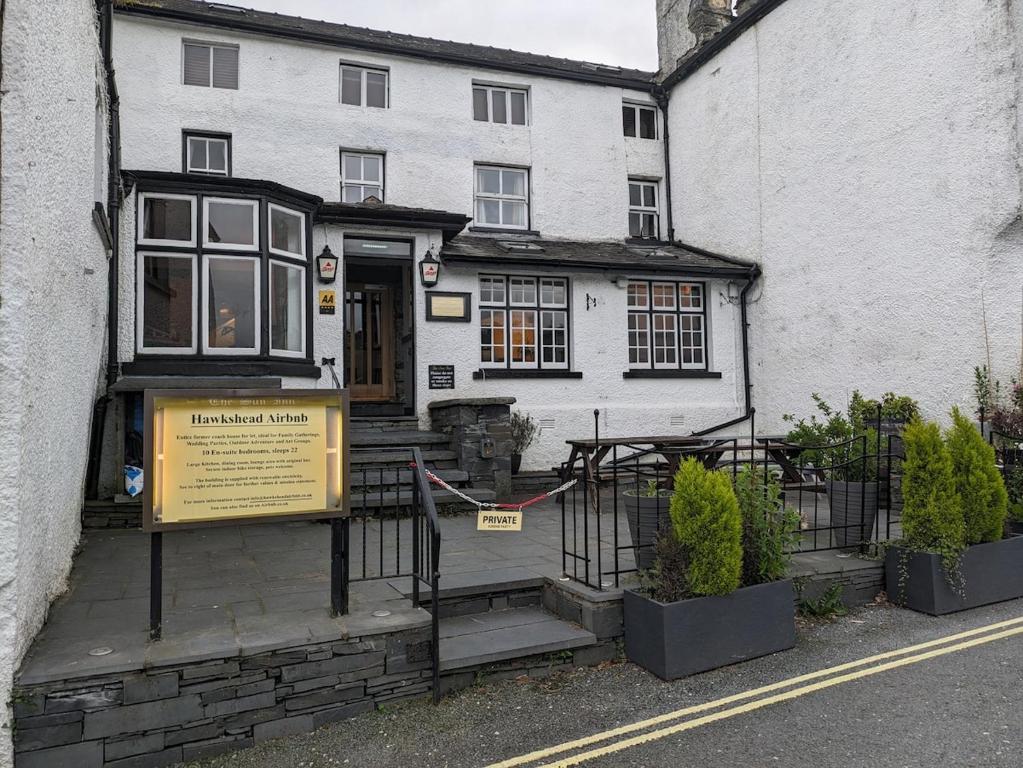 a white building with a sign in front of it at Lake District Pub with 10 en-suite rooms in Hawkshead