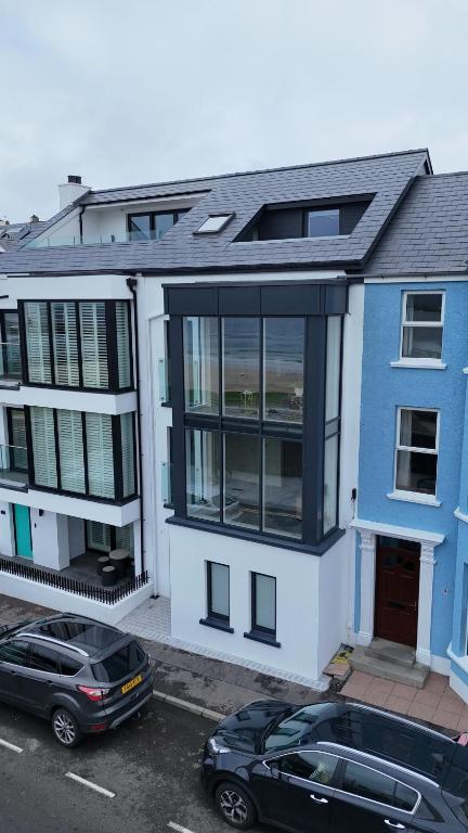 two cars parked in a parking lot in front of a house at Atlantic View - Portrush in Portrush