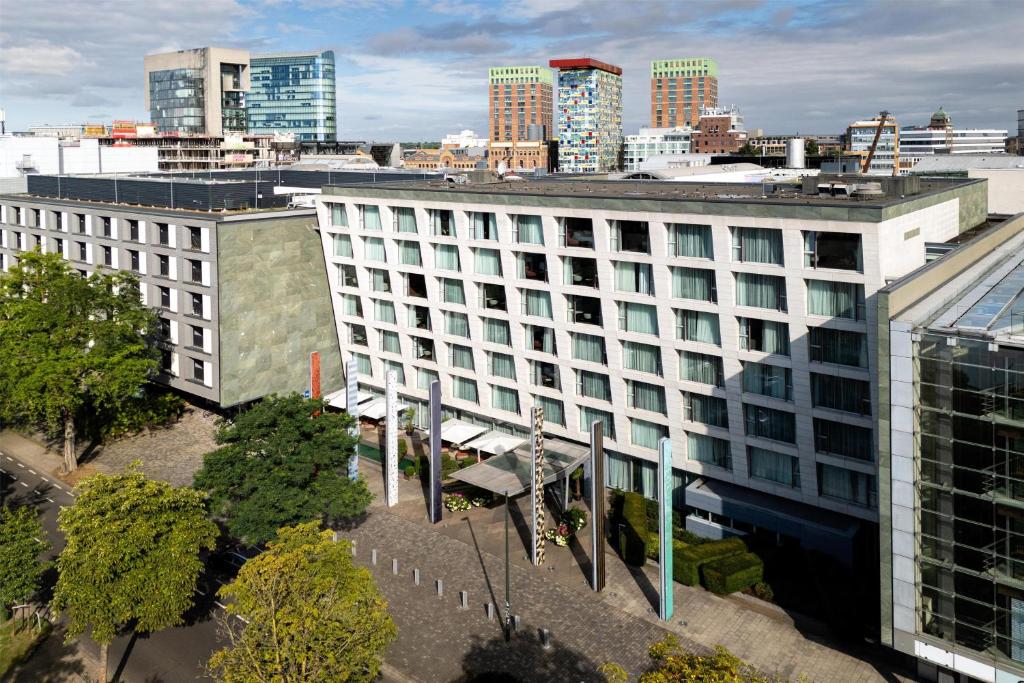 a large white building with a city in the background at Radisson Blu Media Harbour Hotel, Düsseldorf in Düsseldorf