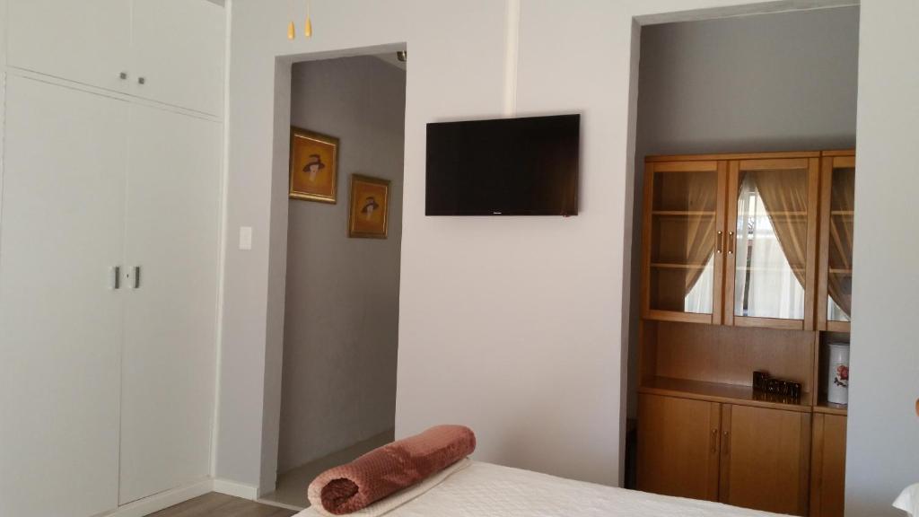a bedroom with a bed and a tv on a wall at Little Acorn Guest House in Welkom