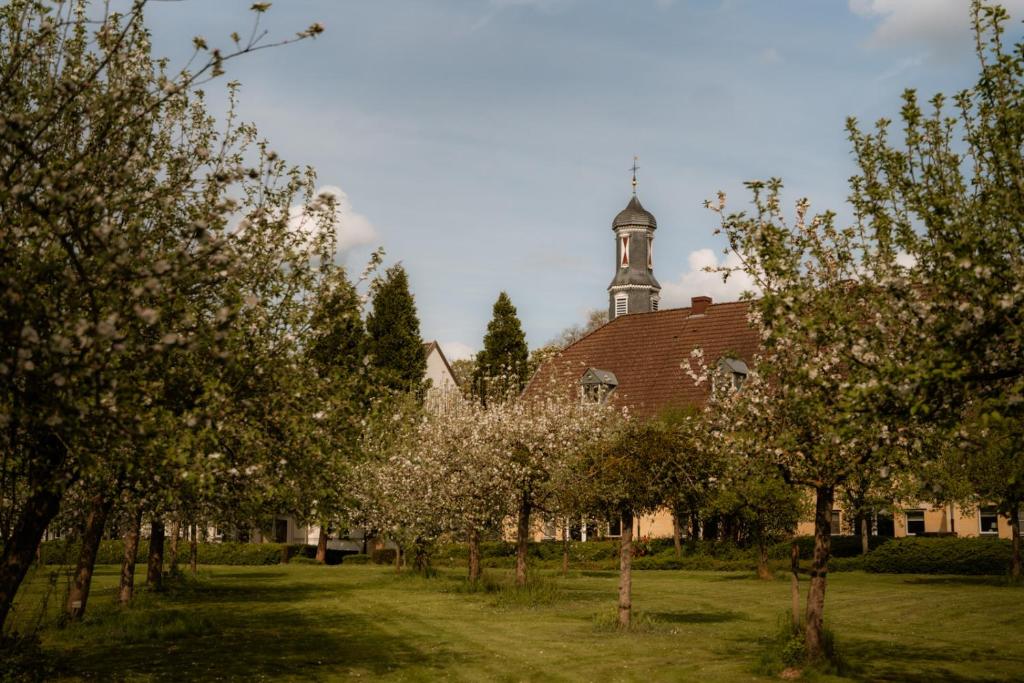 eine Kirche mit einem Turm auf einem Hof mit Bäumen in der Unterkunft Corneli Residenties - Chateau St Gerlach in Valkenburg