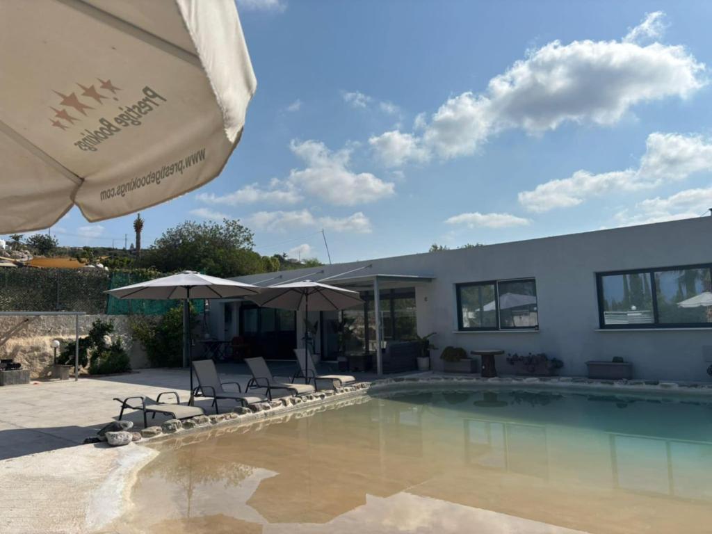 a pool with chairs and umbrellas next to a building at Villa Spilies in Peyia