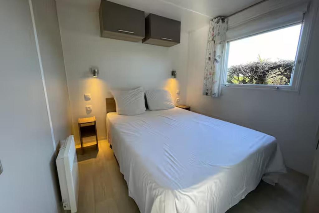 a bedroom with a white bed and a window at Mobile home with shared pool in Saint-Arnoult in Saint-Arnoult