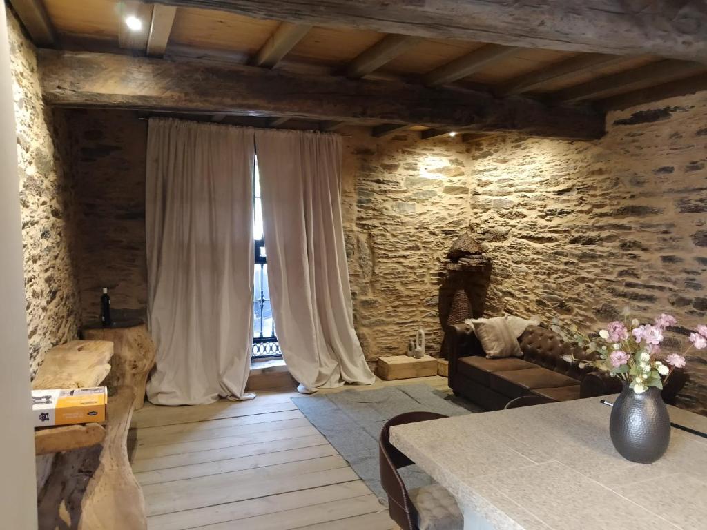 a living room with a table and a stone wall at Dona Remedios in Xermade
