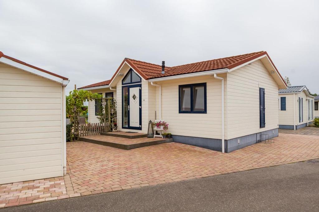 a white house with a brick driveway at Chalet Stalland in Sint Annaland