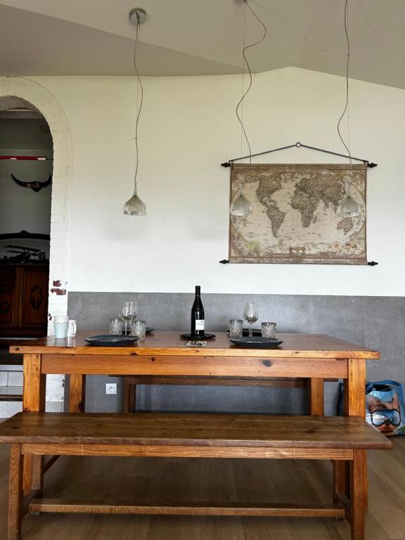 a wooden table with a bottle of wine and a bench at Typic House - Maison piscine CLIM et VUE in Albi