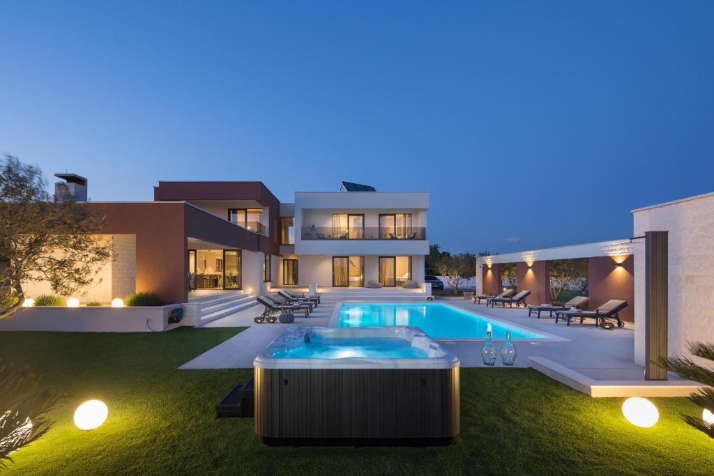 a villa with a swimming pool at night at Villa Scallop ZadarVillas in Podlug