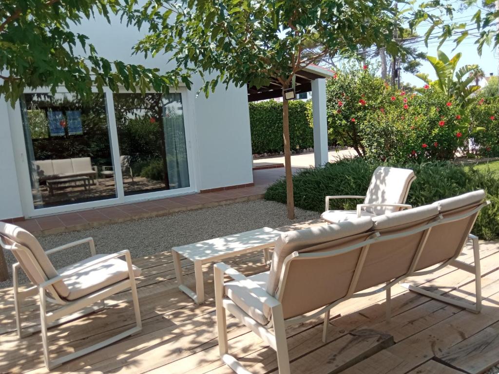 un patio con sillas, una mesa y un árbol en Villa Piscis, en Cala Blanca